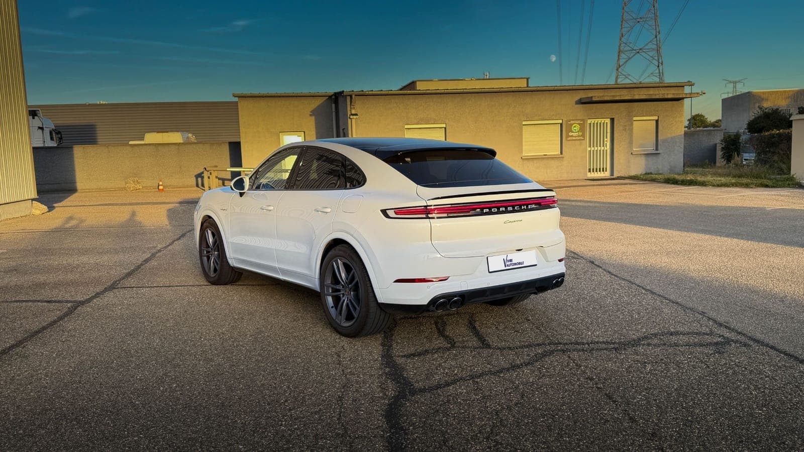 Porsche Cayenne Coupé E-Hybrid blanc vu de trois quarts arrière au coucher du soleil